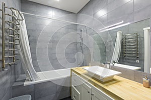 Interior photo of a modern bathroom with gray tiles in a small apartment