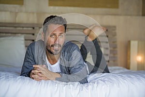 Interior portrait of 30s to 40s happy and handsome man at home in casual shirt and jeans lying on bed relaxed at home smiling