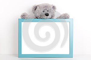 Interior poster mock up for nurcery, children`s room with vertical wooden frame and teddy bear on white wall background
