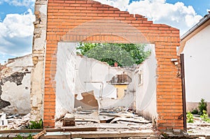 Interior remains of hurricane or earthquake disaster damage on ruined old house in the city with collapsed walls, roof and bricks