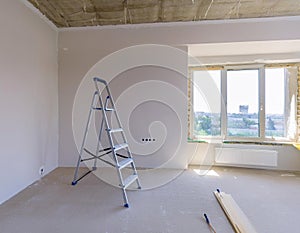 Interior renovation of an empty room with stepladder and construction materials