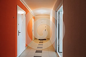 Interior of a residential building in white and orange colors with entrance doors