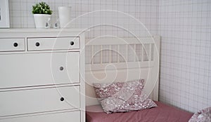 The interior of the room in beige and pink tones with a bed and pillow, closet and flowers on it