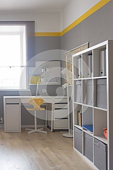 The interior of the room of a boy or girl student in light white and yellow tones, the student's desk in the room at