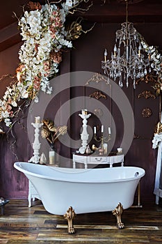 The interior of the room is in vintage style. A large bathtub. Decoration with flowers