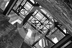 Interior of a ruined old industrial building, looking up at roof girders