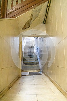 interior of a run-down residential building with stairs leading up to an illuminated exterior.