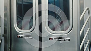 Interior shot of closed New York City subway underground train car doors during motion, warning lean signs on both sides