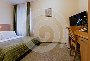 Interior of a simple and nicely furnished cozy hotel room with a double bed during daytime
