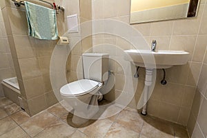 Interior of simple spacious empty bathroom equipment, sink, toilet and shower cabin on copy space background of light beige tile