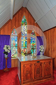 Interior of a small church, with altar and stained glass windows