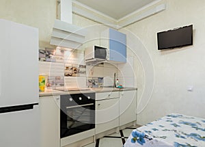 The interior of a small kitchen with a TV on the wall photo