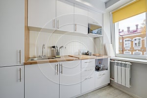 Interior of the small living equipped kitchen in studio apartments in minimalistic style with light color