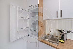 Interior of the small living equipped kitchen in studio apartments in minimalistic style with light color