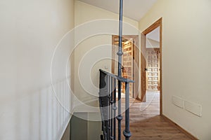 Interior staircase of a duplex residential house with metal railings, Castilian-style wooden panel doors and wooden floors