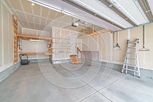 Interior of an unfinished garage with wooden shelving units and stairs to a white door