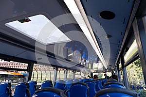 Interior of the upper deck in a modern double-decker bus with ceiling and blue seats