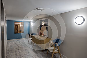 Interior view of corridor area near elevator doors reveals setup furnished with chairs for comfort of hotel guests.