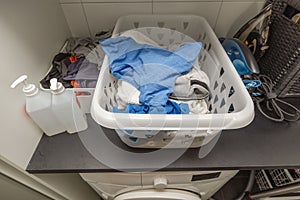 Interior view of laundry cabinet.  Basket with clean clothes and iron over washing machine