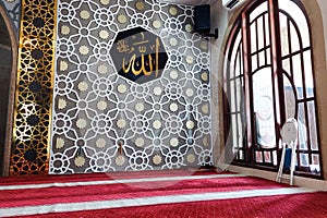 An interior view of a mosque featuring a beautifully decorated wall with Islamic