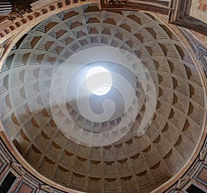 Interior view upward to the coffered concrete dome of Roman Pantheon with famous sunbeam and circular opening oculus in photo