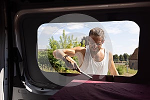 Man using a file to deburr a window opening in a camper van
