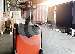 Interior of warehouse dock. Electrick forklift pallet jack and shipment pallet boxes waiting for load into container truck.