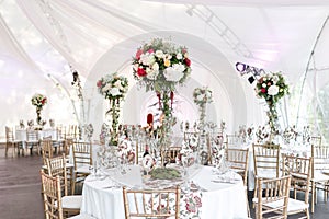 Interior of a wedding tent decoration ready for guests. Served round banquet table outdoor in marquee decorated flowers