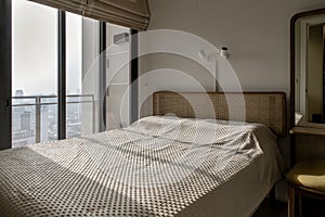 Interior white bedroom with brown curtains and white pillows, blanket on wooden bed classic illuminated by sunlight in the morning