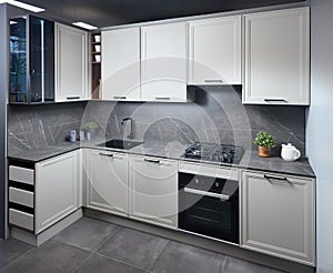 Interior of white and grey kitchen, horizontal, linear layout. Luxury modern fitted flat design kitchen with glass