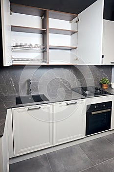 Interior of white and grey kitchen, horizontal linear layout. Luxury modern fitted flat design kitchen with opened