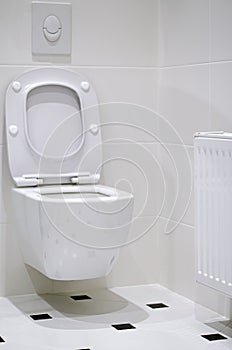 Interior. A white toilet bowl hangs on a white tile wall in a white bathroom