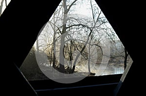 Interior window view from covered bridge on rural river and woods