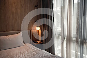 Interior of wooden bedroom with curtain and glowing lamp