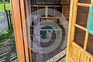 Interior of a wooden henhouse in the countryside seen through an open door.