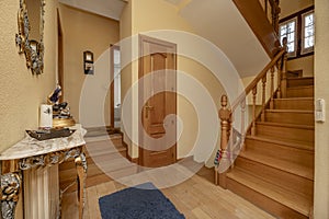 Interior wooden stairs in a house with wooden furniture, oak carpentry on doors and railings of the same material