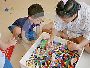 Interlocking plastic bricks in mother`s hands being built with help from her little baby