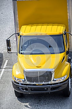 Intermediate rig yellow semi Truck with box trailer running on the road