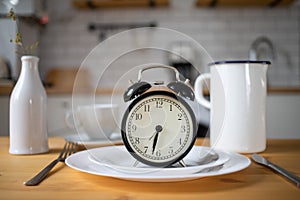 intermittent fasting concept alarm clock on kitchen table