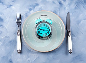 Intermittent fasting concept with blue alarm clock