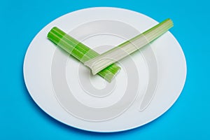 Intermittent fasting, diet concept. An empty plate as a dial and pods of a seler as a clock hands on a blue background