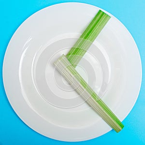 Intermittent fasting, diet concept. An empty plate as a dial and pods of a seler as a clock hands on a blue background