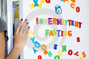 Intermittent fasting diet concept with woman standing in front of fridge starring at food