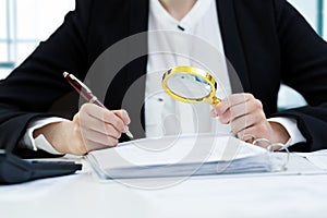 Internal audit concept - woman with magnifying glass inspecting photo