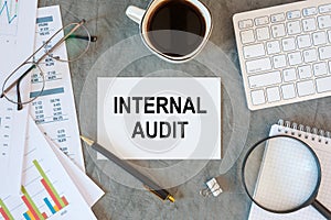 INTERNAL AUDIT is written in a document on the office desk, coffee, keyboard and smartfon