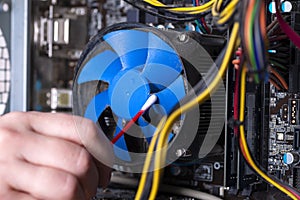 Internal parts of an old personal computer. Dusty motherboard, video card and fan. The master cleans the PC cooler from