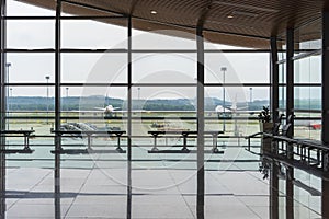 International airport interior corridor with seats and glass frame and reflections window in airport terminal departure hall