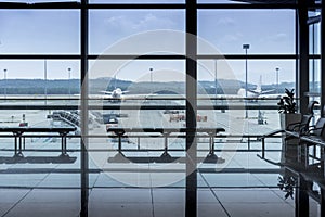 International airport interior corridor with seats and glass frame and reflections window in airport terminal departure hall