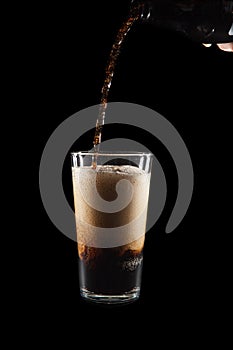 International Beer Day. Stout ale being poured in to a pint glass. Against black background.