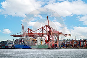 International cargo ship with containers cargo cranes and helicopter flying on port at coastline